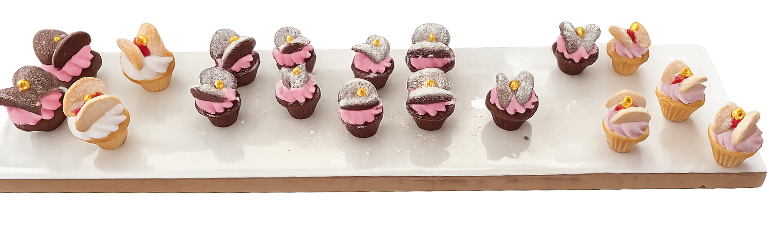 Assorted miniature cupcakes with pink and white frosting, some topped with chocolate or cookie pieces and gold decorations, arranged on a long white platter.