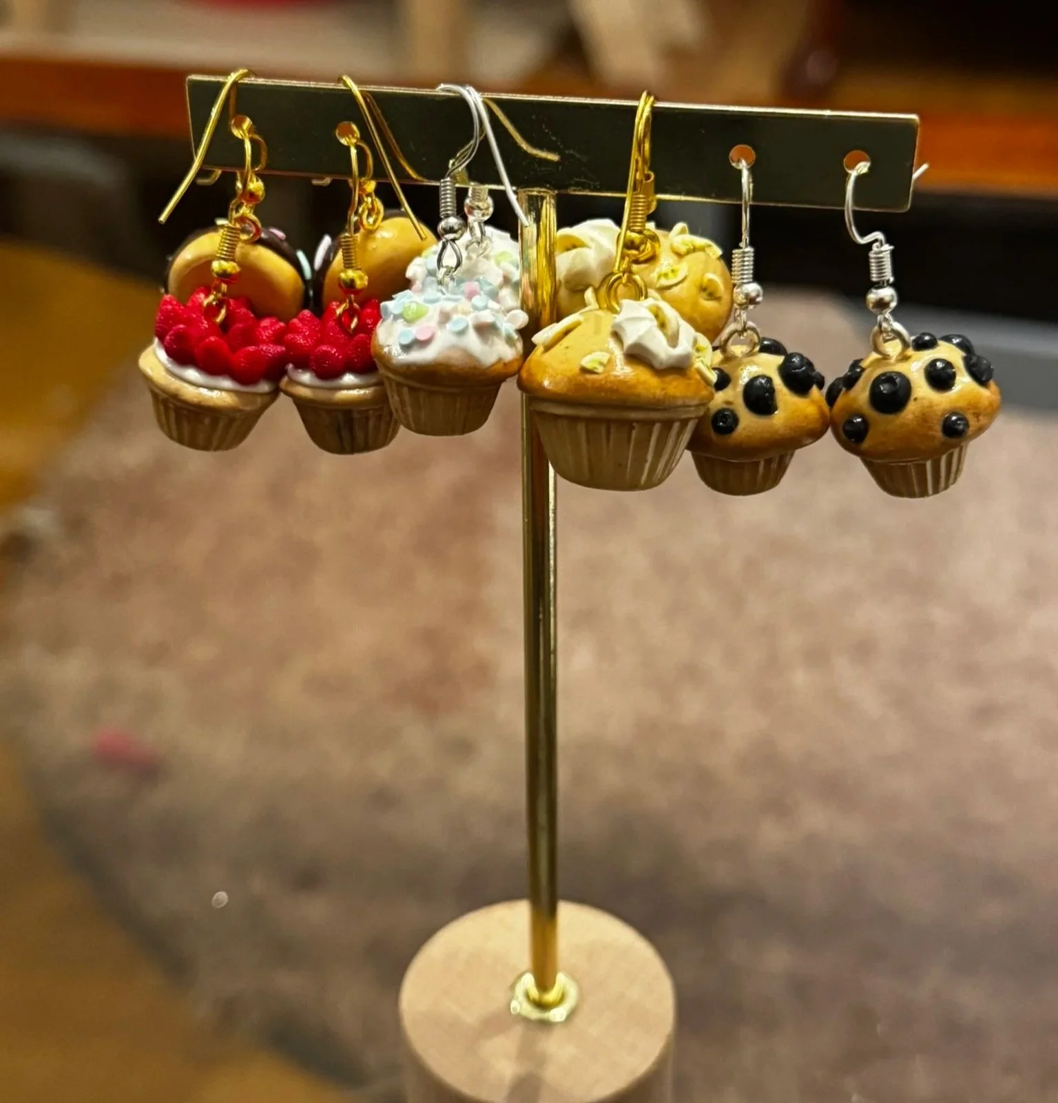 Miniature cupcake earrings and cupcake charms displayed on a jewelry stand.