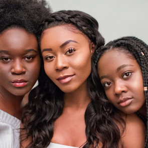 Close-up of three Black women with natural hairstyles and neutral expressions