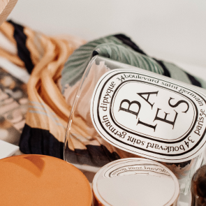 Close-up of a glass bowl with a logo, surrounded by fabric and a pumpkin.