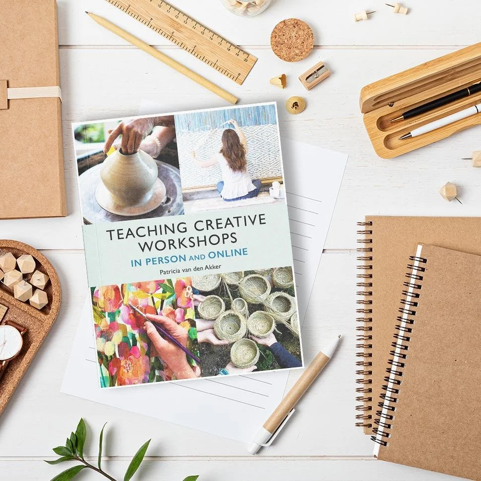 A creative workshop flyer on a desk surrounded by notebooks, pens, a ruler, and art supplies.