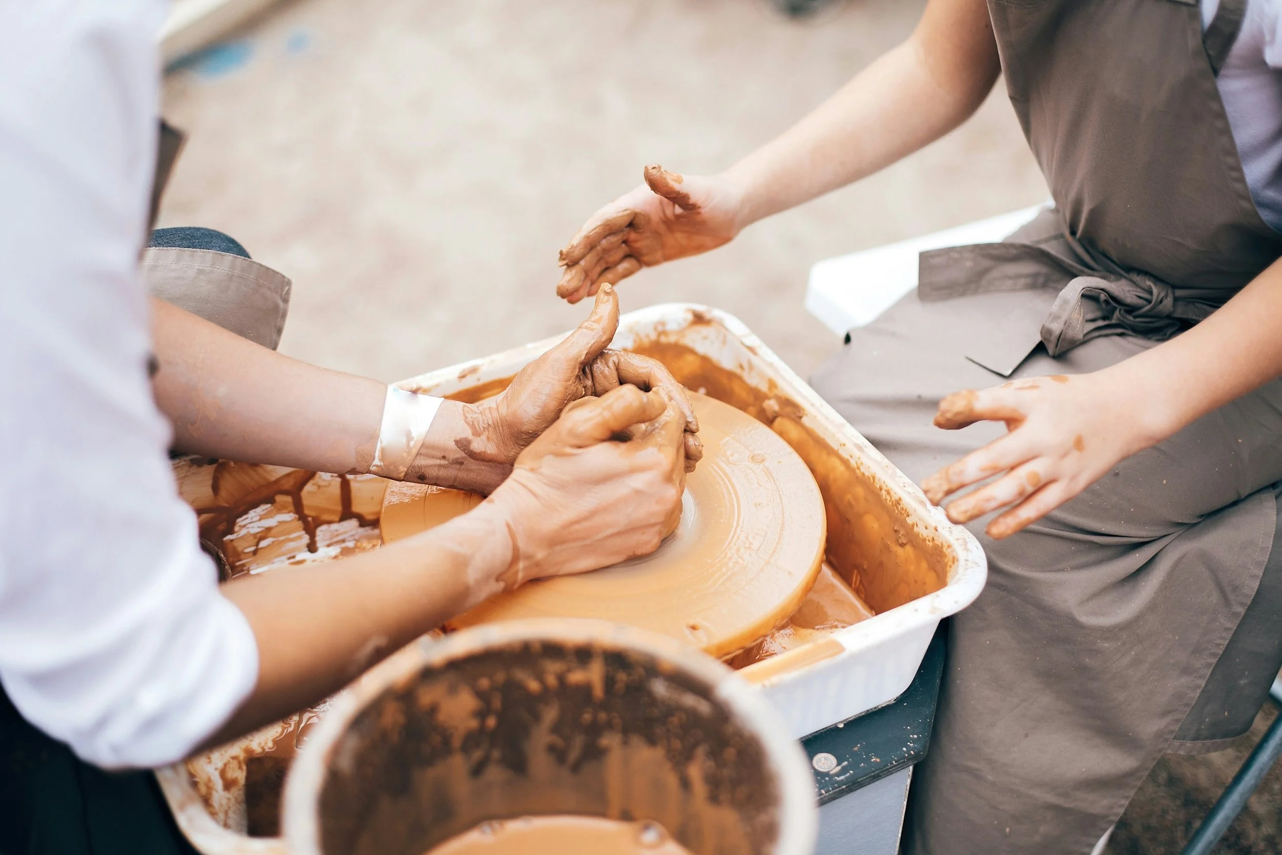 Hands working with clay on a pottery wheel in a pottery workshop.