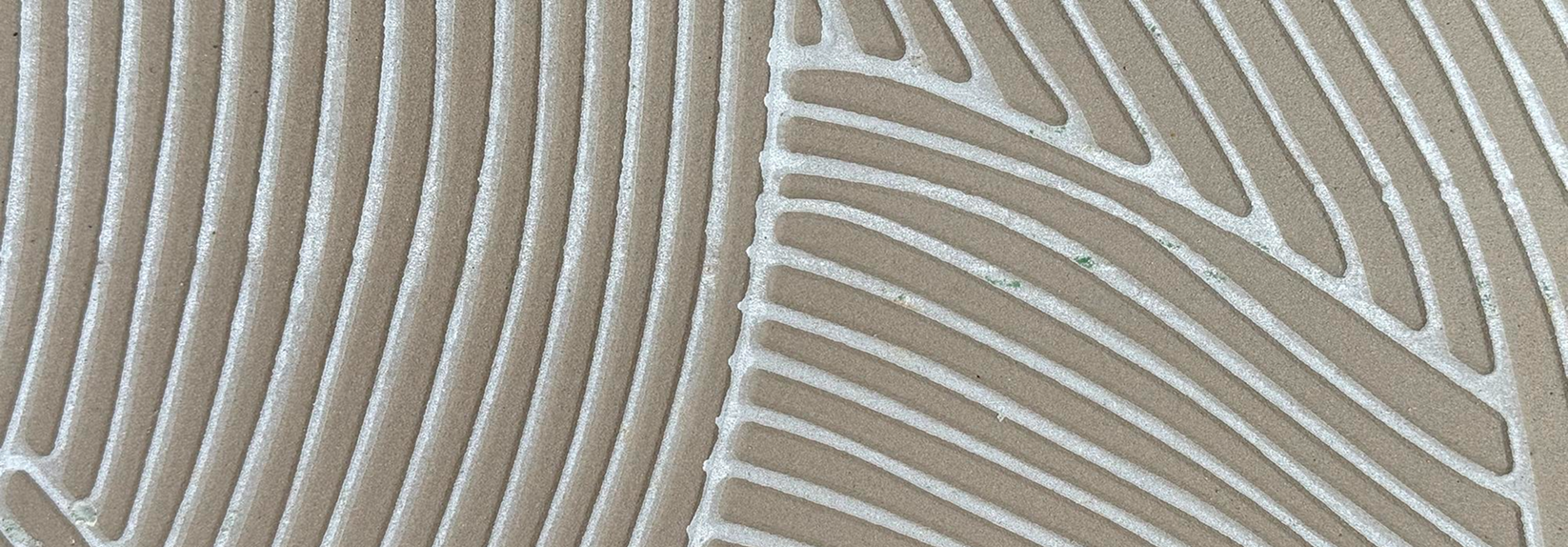 Close-up of a decorative outdoor floor made of beige tiles with white lines creating geometric patterns.
