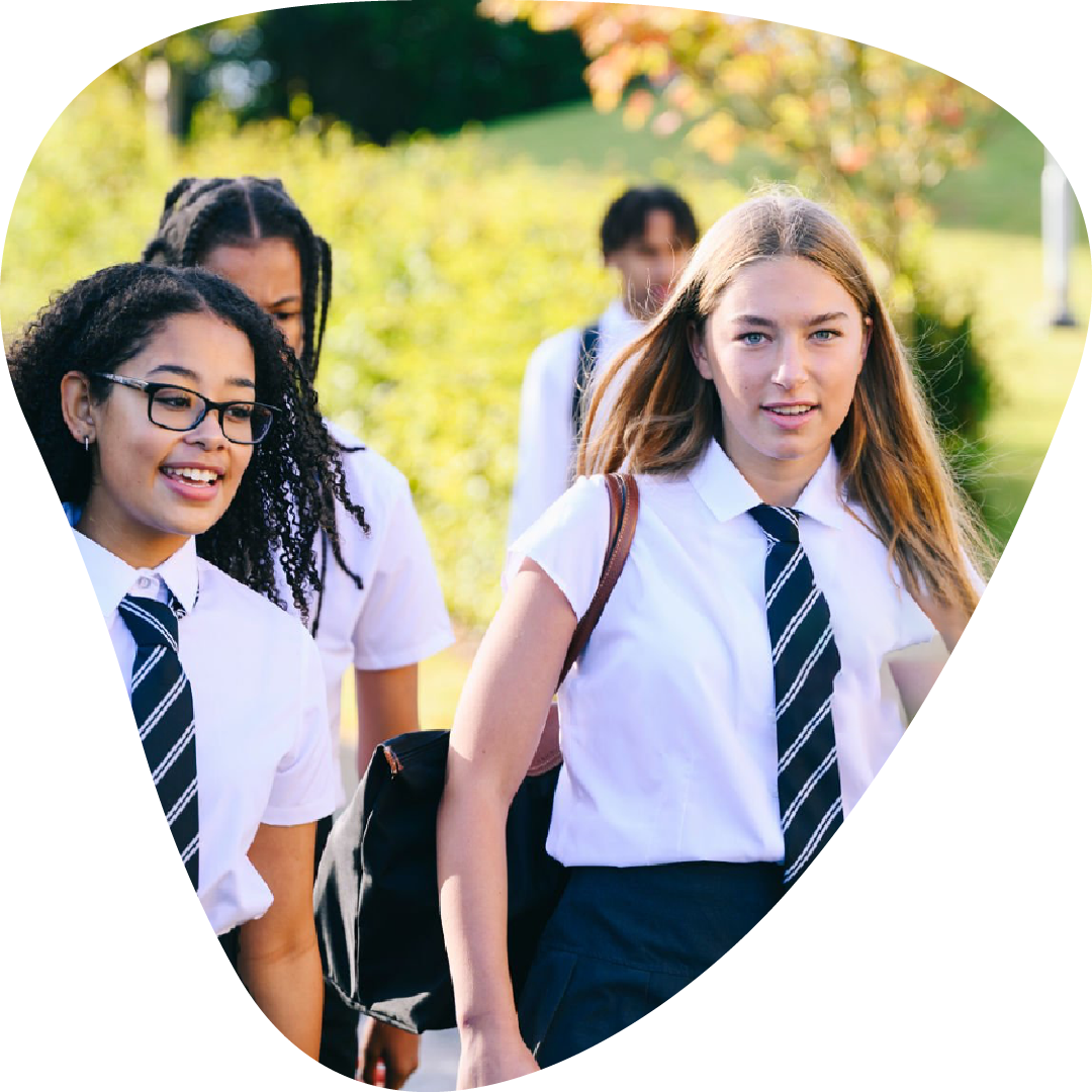 Group of female students in school uniforms walking outside school on a sunny day.