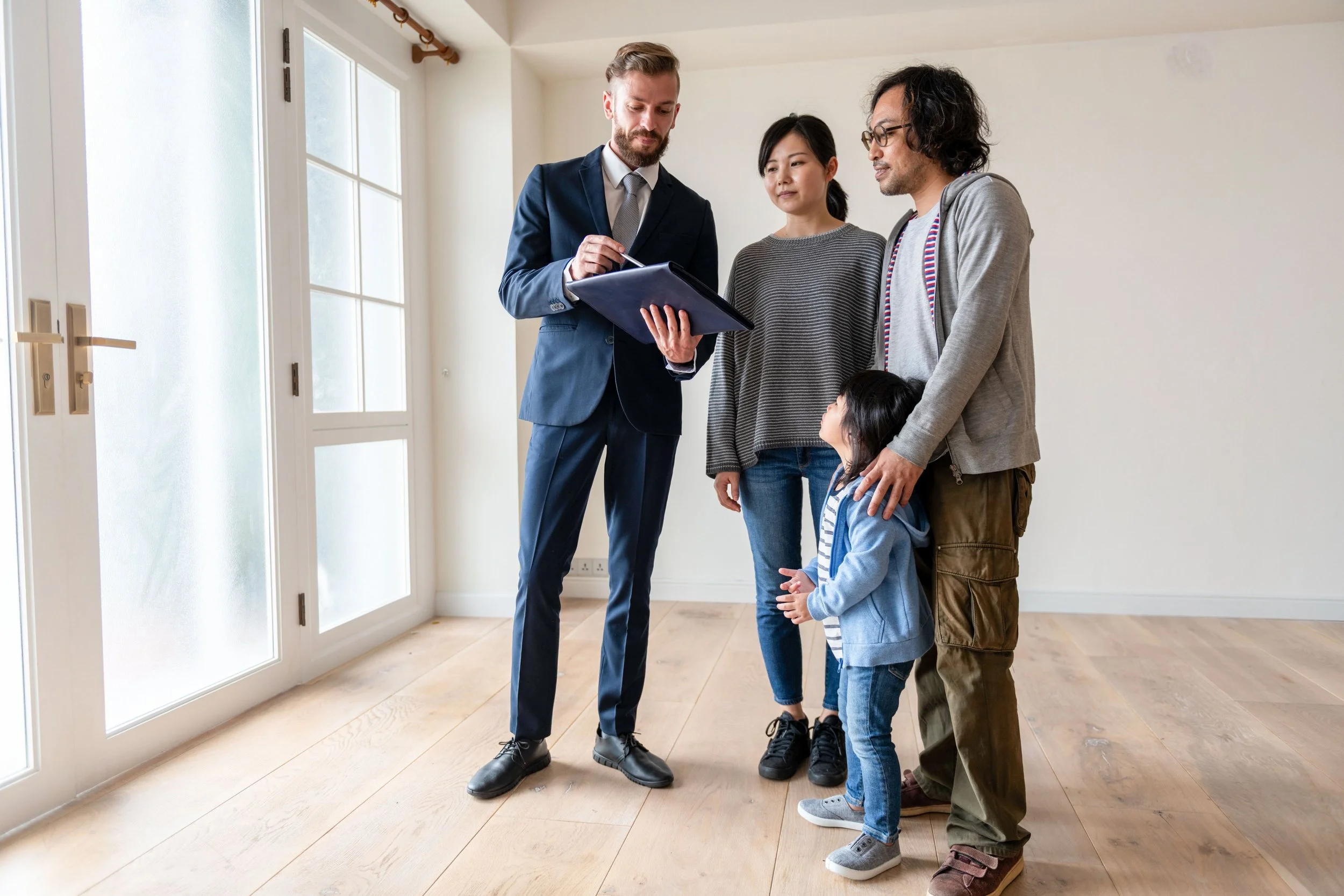 A real estate agent showing a couple and their young daughter a house.