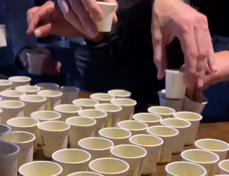Kleine Probierbecher mit verschiedenen Olivenölen, die für ein Olivenöl-Tasting vorbereitet wurden. Teilnehmende der Veranstaltung nehmen sich die Becher um diese zu testen und zu probieren.