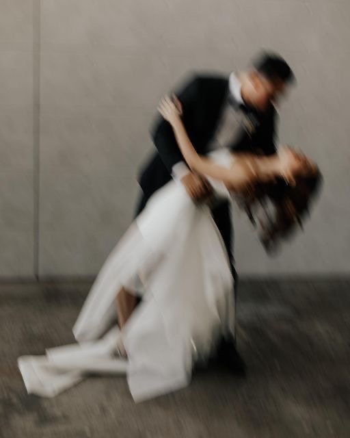 A couple dancing; the woman is in a white dress leaning backward, and the man is in dark clothing supporting her as they dance closely.