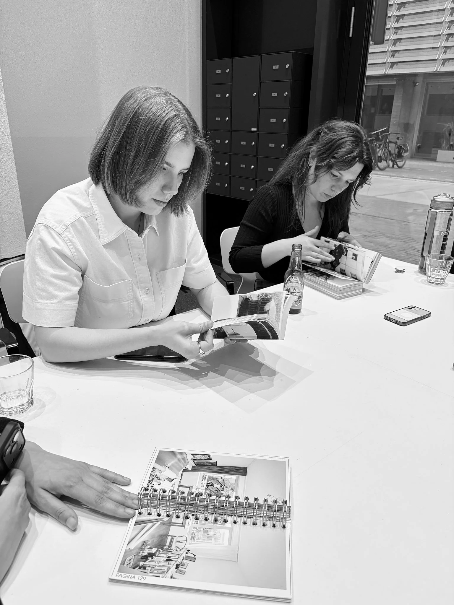 Two participants seated at a table leaf through photobooks and a spiral-bound dummy during a Wanderstories edition.