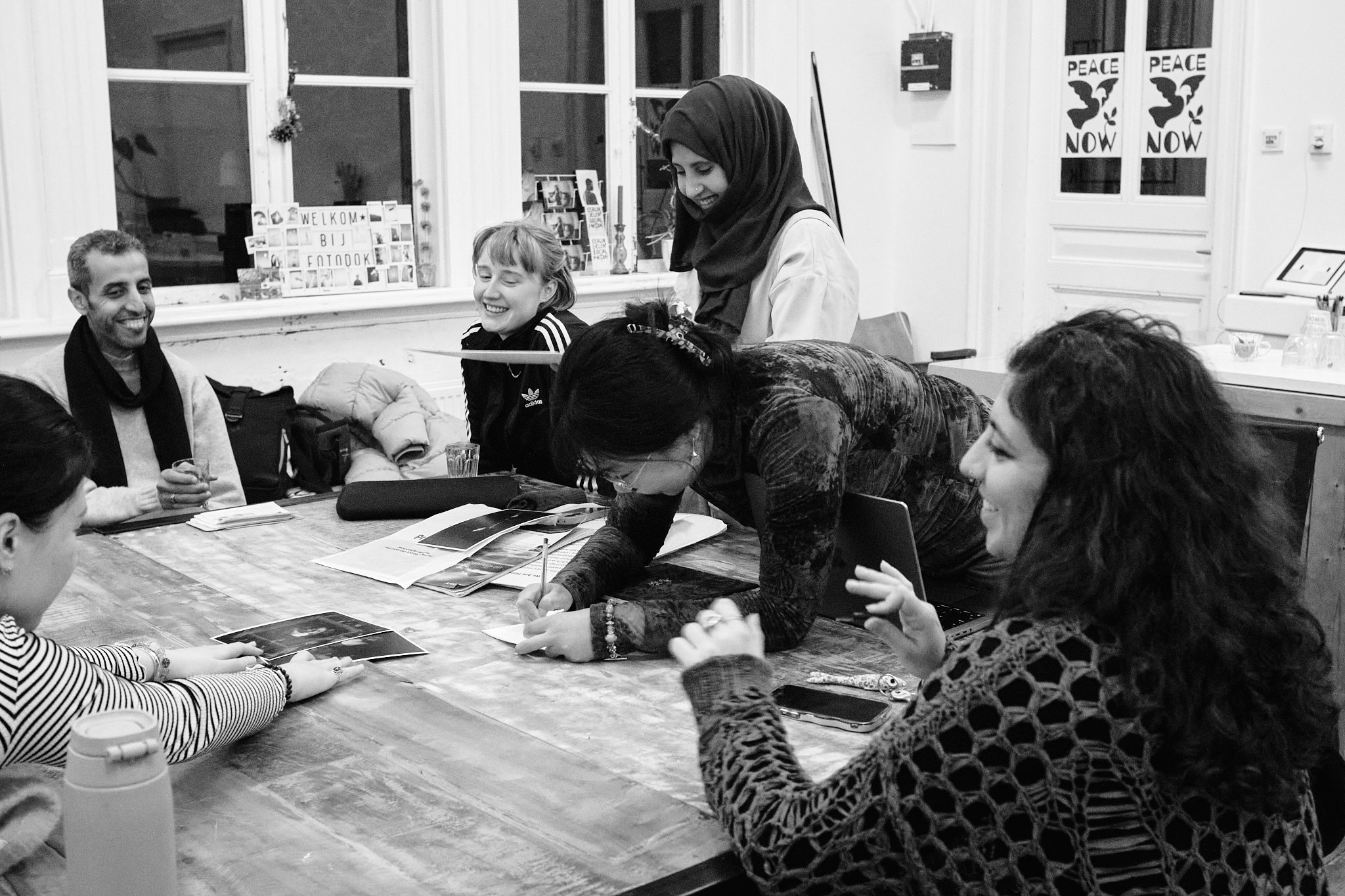 A relaxed moment during a Wanderstories session: participants laugh and talk around a table scattered with prints and notes.