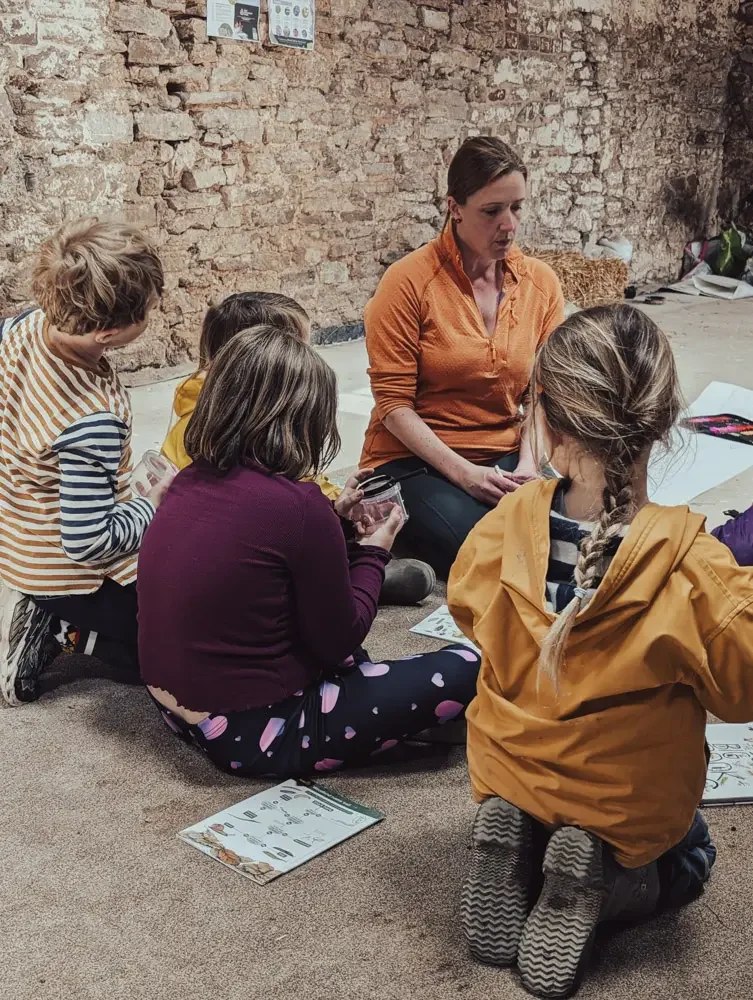 Children sitting in a circle with their teacher during an outdoor lesson at Eyton Burrow