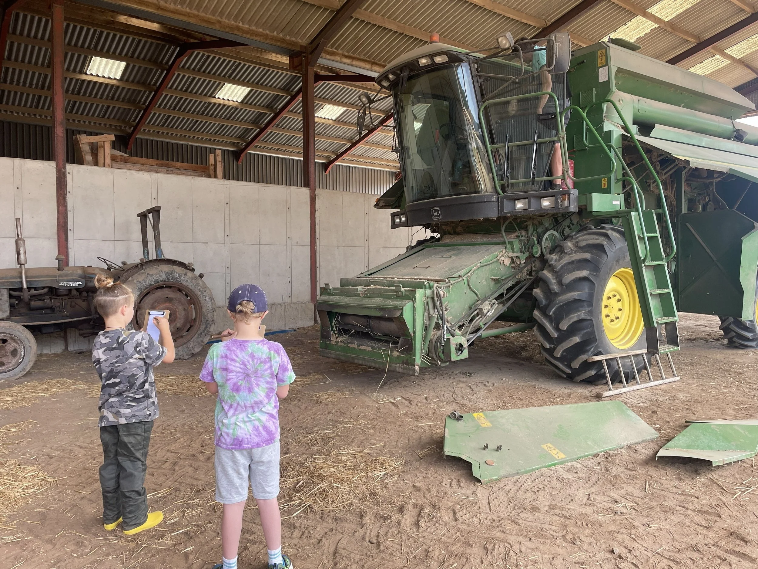 Children sitting in and sektching the combine harvester at harvest time