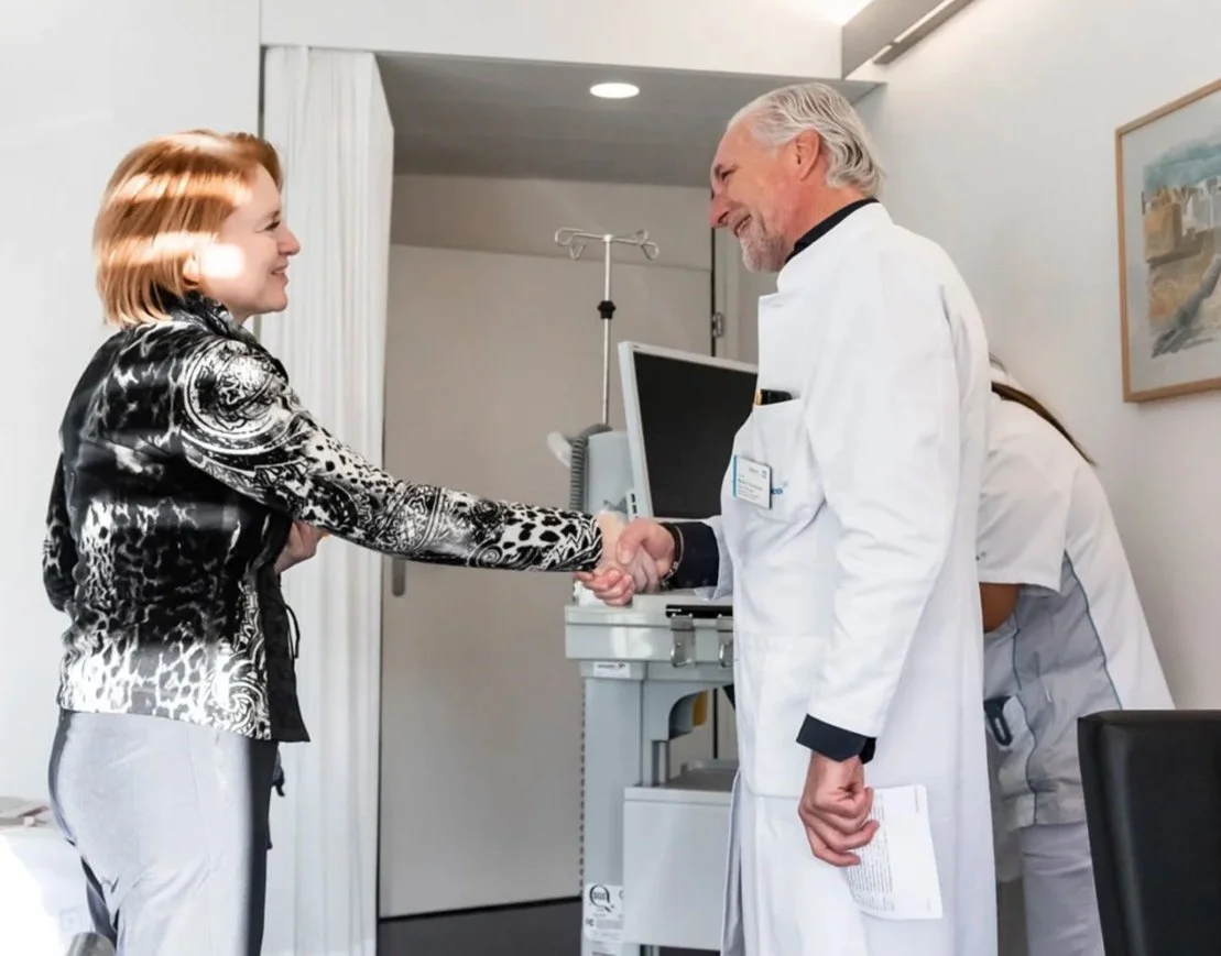 Ärztinnen und ein Patient beim Händeschütteln im Krankenzimmer.