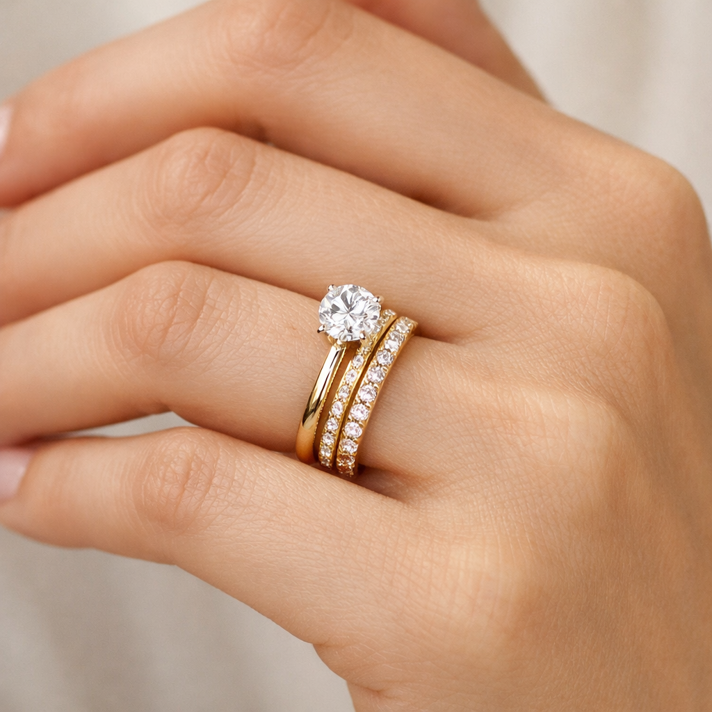 Close-up of a woman's hand with a gold engagement ring featuring a large center diamond, and a matching gold wedding band with smaller diamonds.