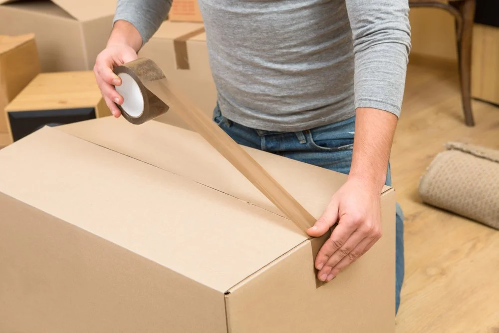 Macomb Movers securely packing household belongings and sealing moving boxes for a safe residential relocation in Macomb County, Michigan.