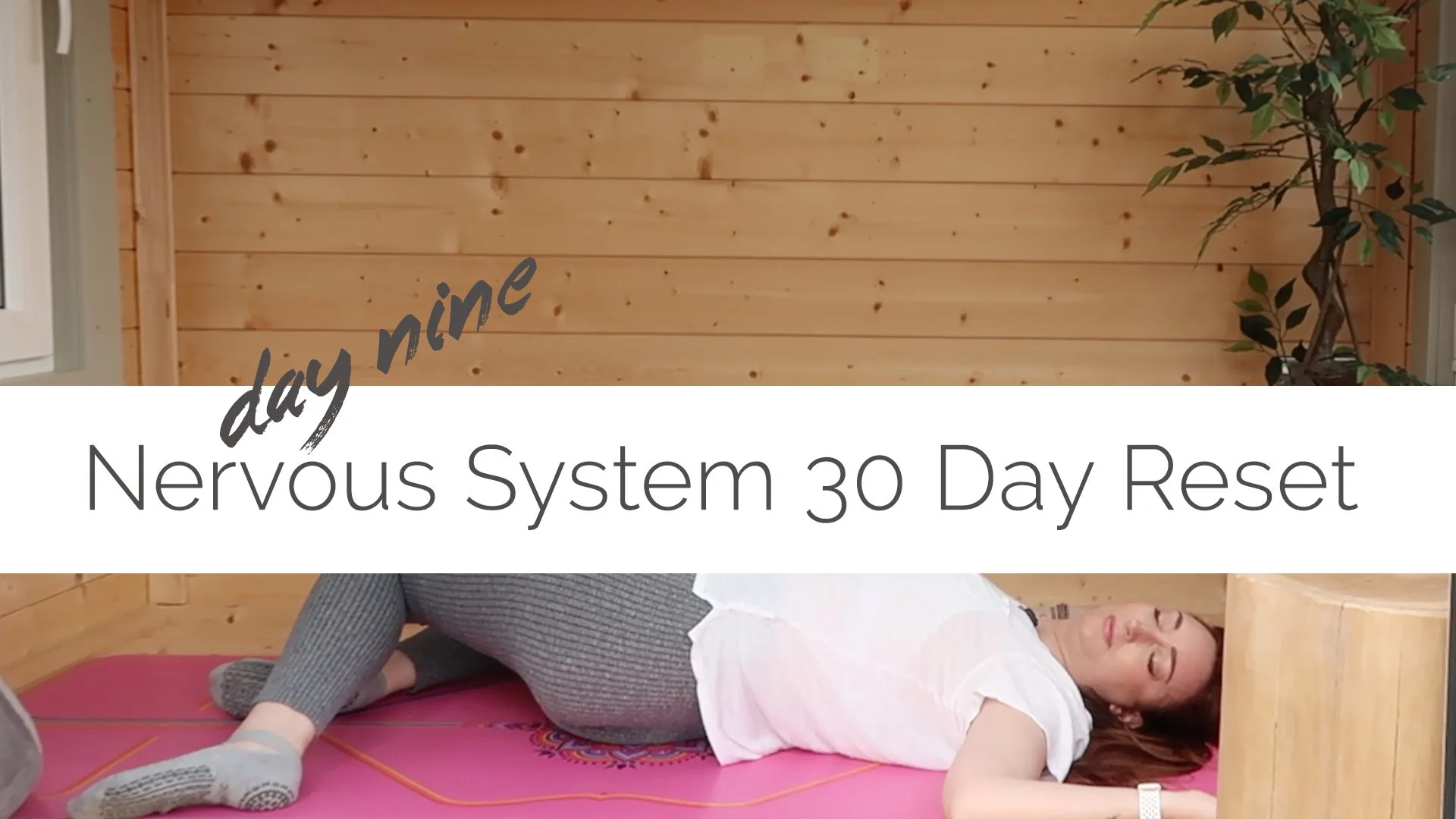 A woman lying on her side on a yoga mat in a wooden room, receiving a treatment called 'Nervous System 30 Day Reset'.