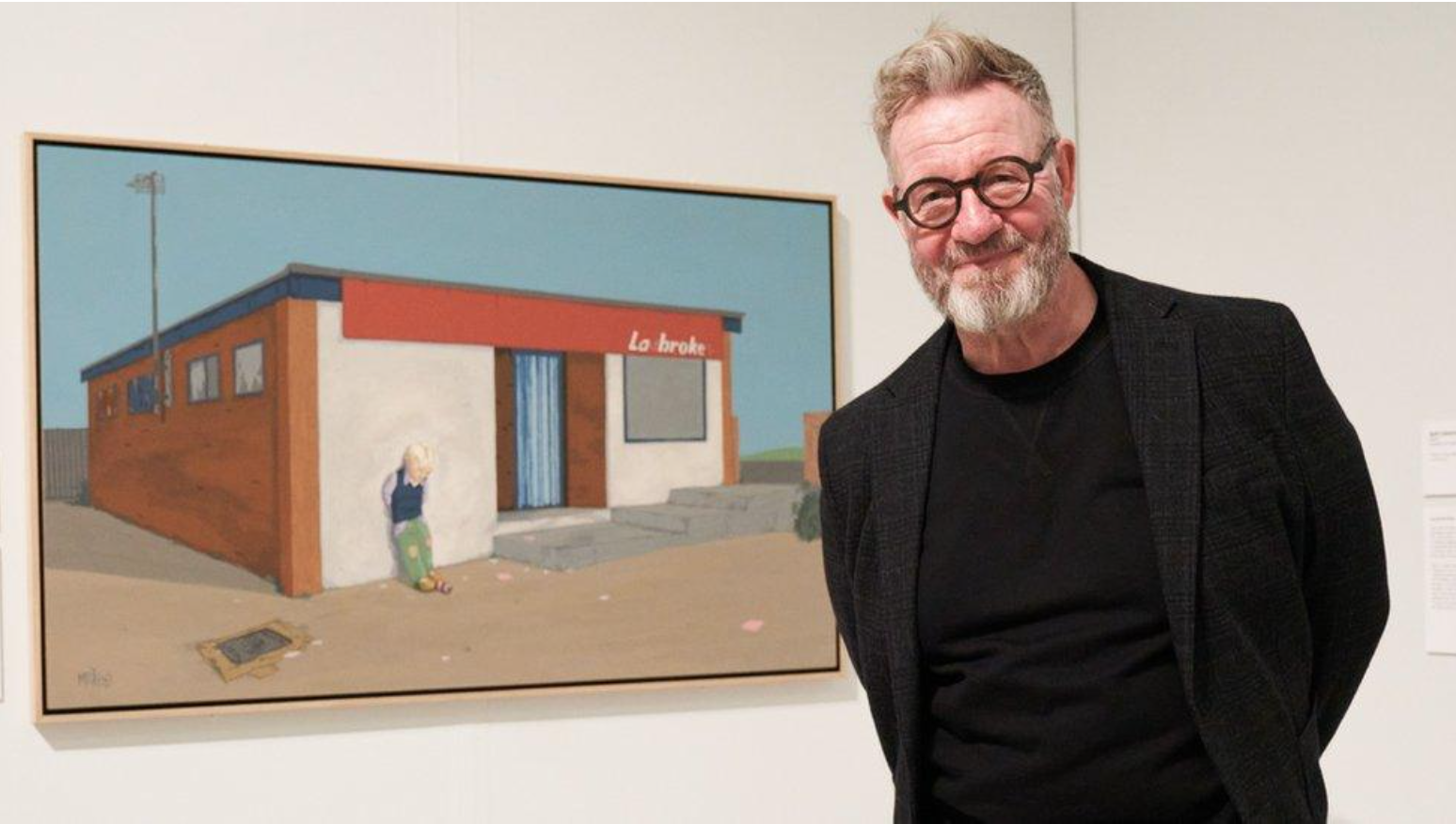 Pete McKee standing in front of his painting La Brok