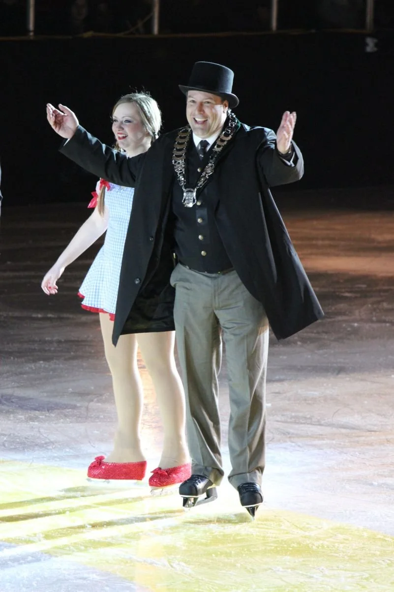  	
Mayor Steve Pellegrini on ice at an indoor rink, celebrating and smiling. 