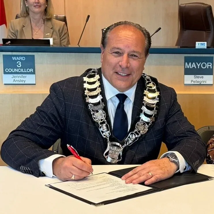 Mayor Steve Pellegrini sitting at a desk signing a document.
