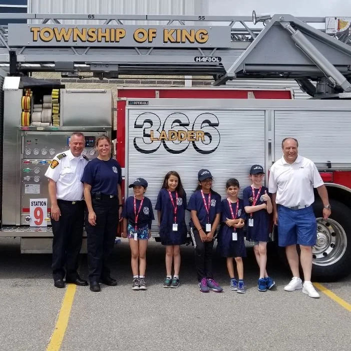 Children and adults standing in front of a fire truck with 'Township of King' sign, posing with Mayor Steve Pellegrini for a photo during a community event.