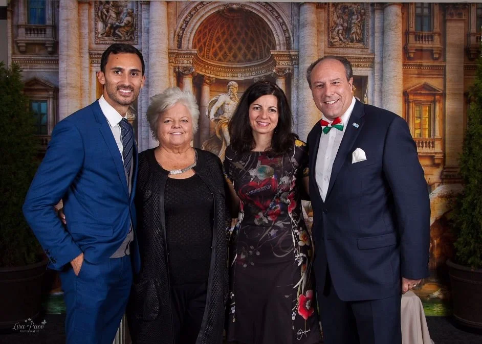 Mayor Steve Pellegrini and Stephen Lecce standing together, smiling, in formal attire in front of a grand architectural backdrop with columns and statues.