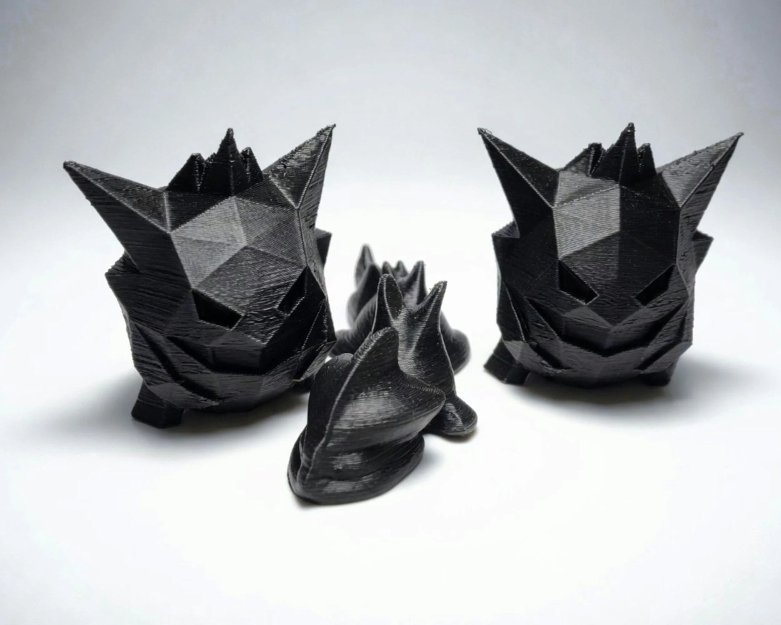 Black 3D-printed wolf head sculptures with multiple pointed ears, set against a plain white background.