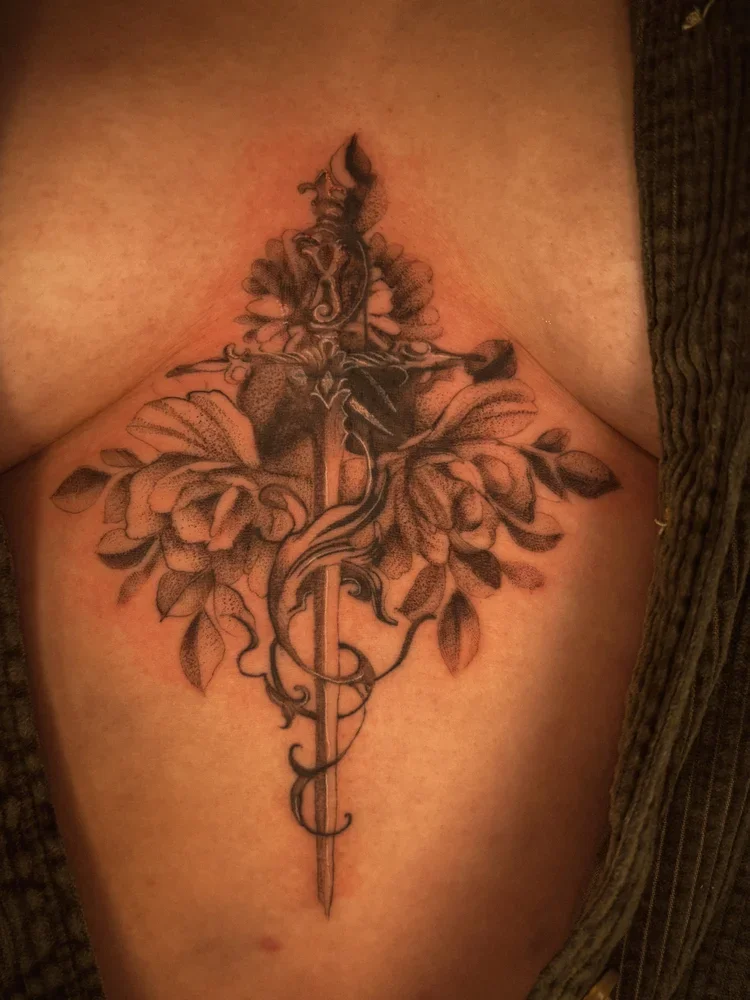 Tattoo of two hummingbirds, one flying above the other, surrounded by floral designs on a person's upper arm.