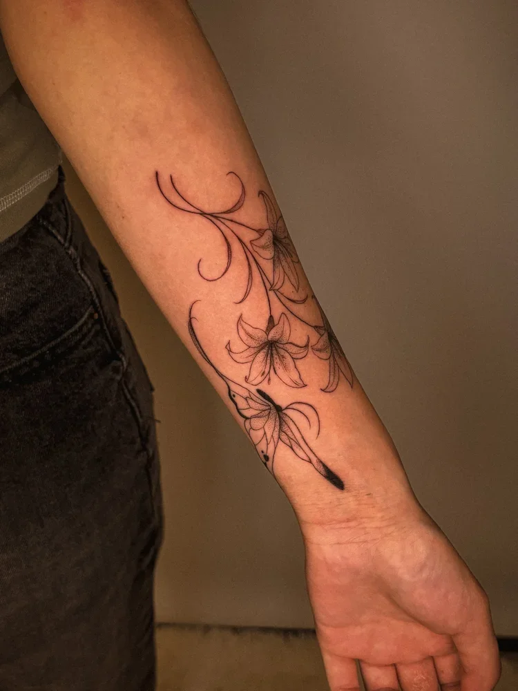 Tattoo of flowers and a butterfly on a person's forearm.
