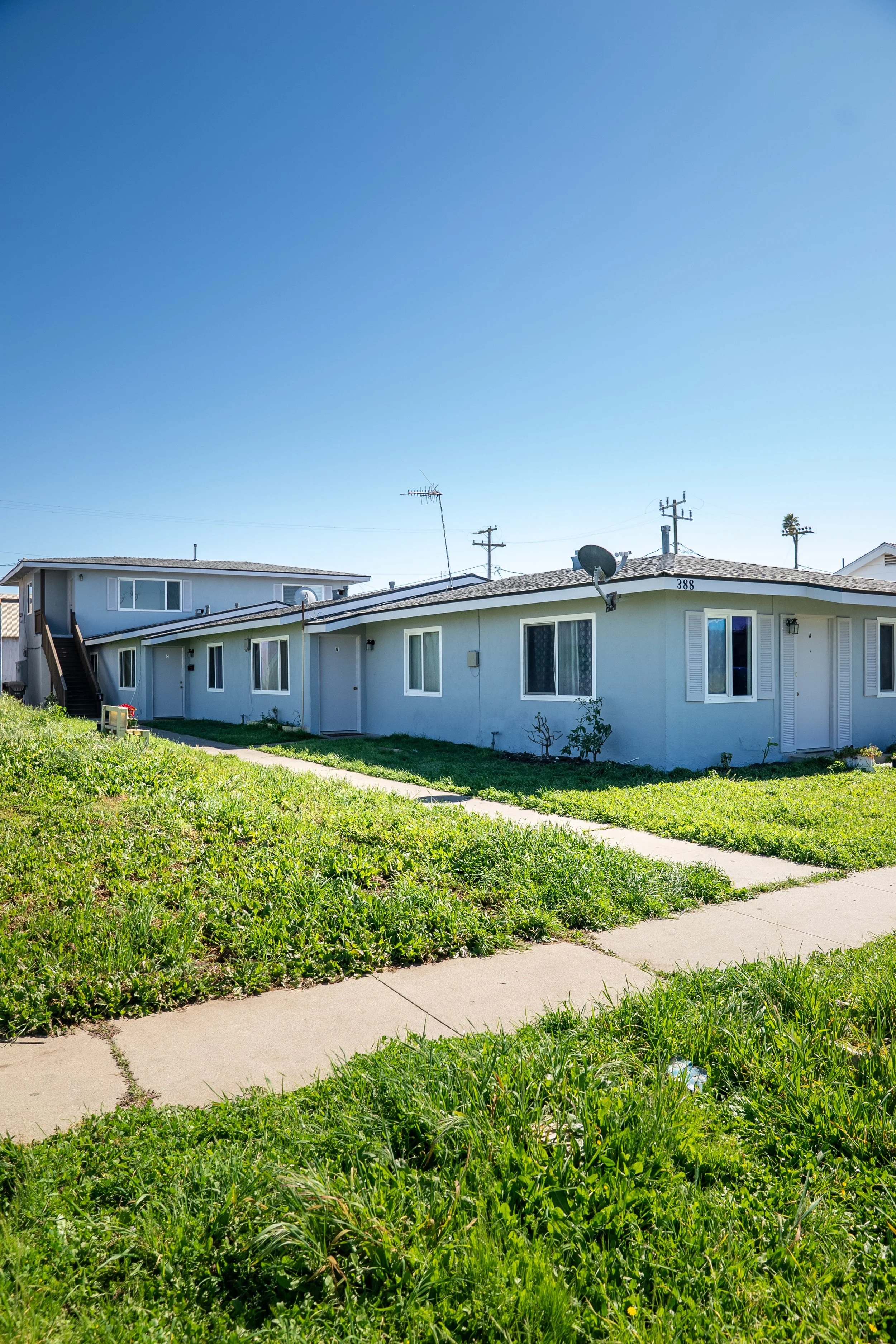 Apartment building with a green lawn, sidewalk, and clear blue sky.