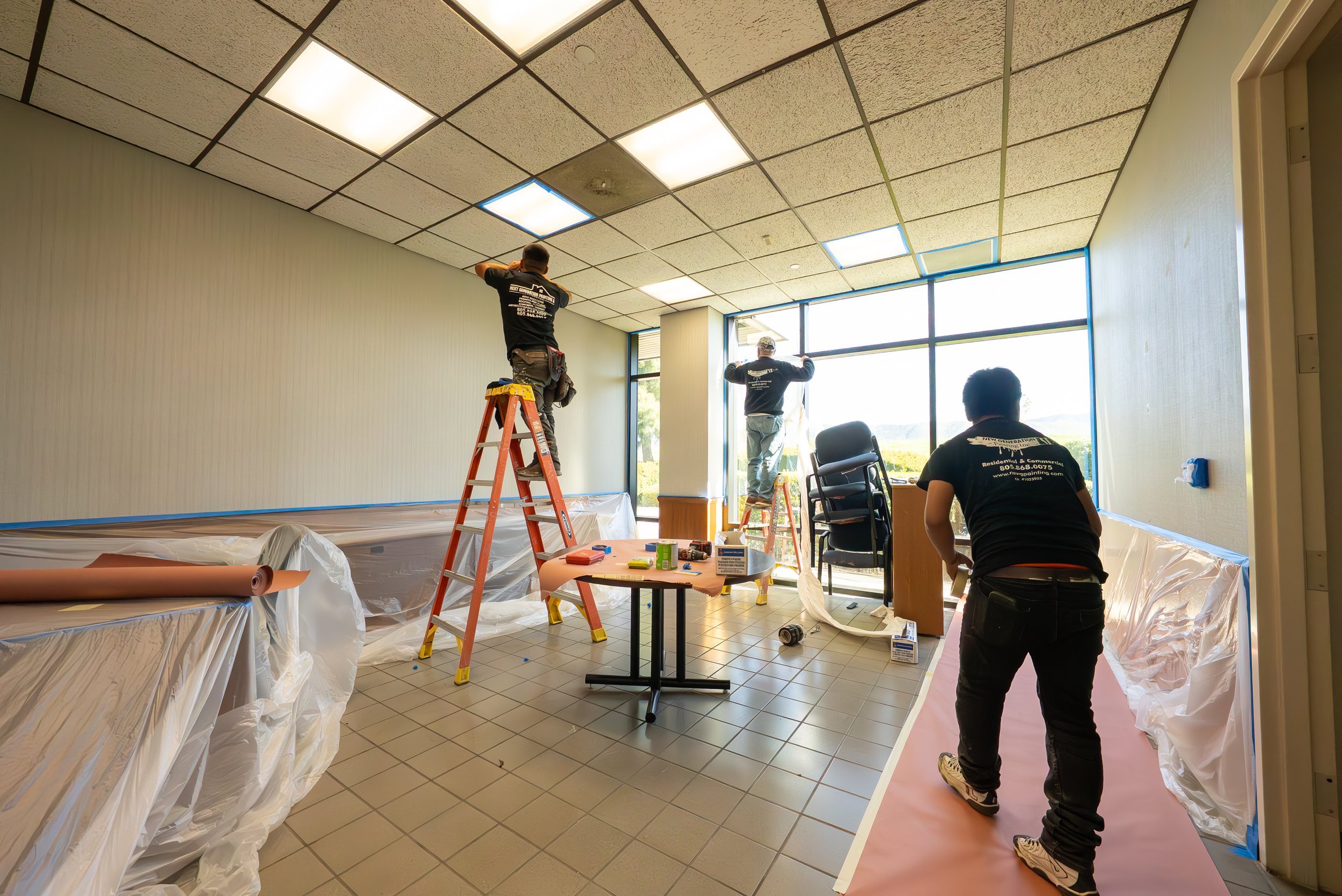 Workers installing ceiling tiles in a commercial building.