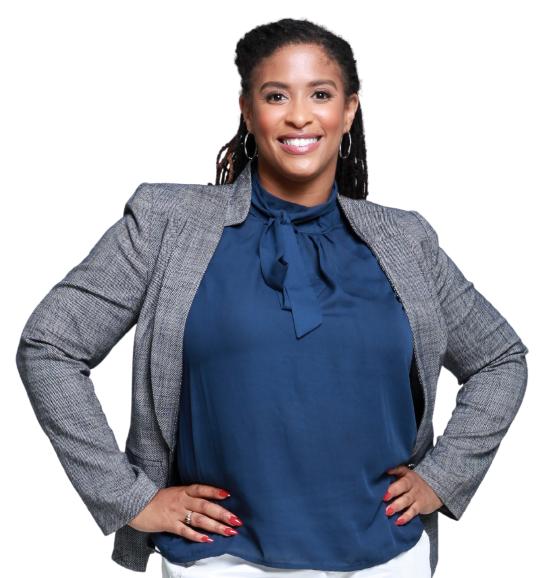 A confident woman with long black hair, wearing a gray blazer over a blue blouse with a bow, smiling with hands on hips.