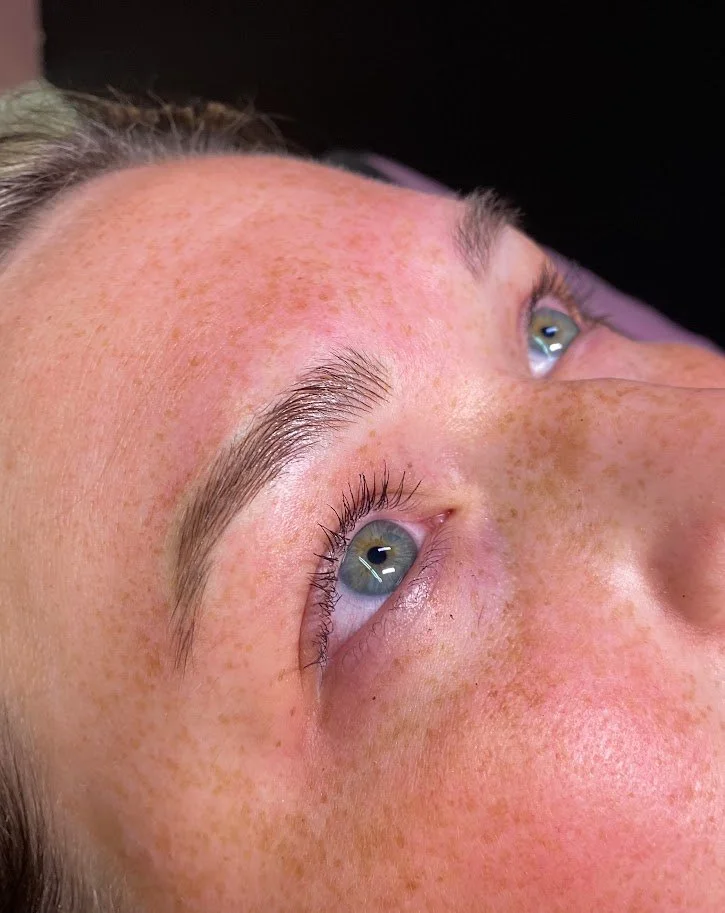 Close-up of a person's face with light skin and freckles, lying on their back, showing their blue eyes, eyebrows, and forehead.