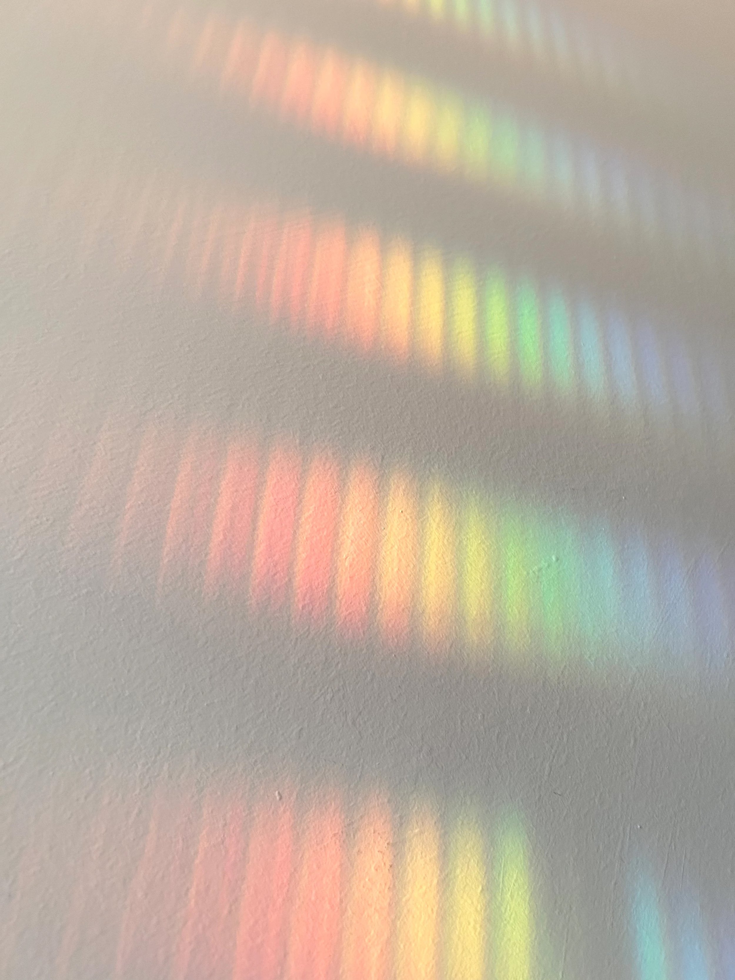 Rainbow-colored light reflection on a white wall.