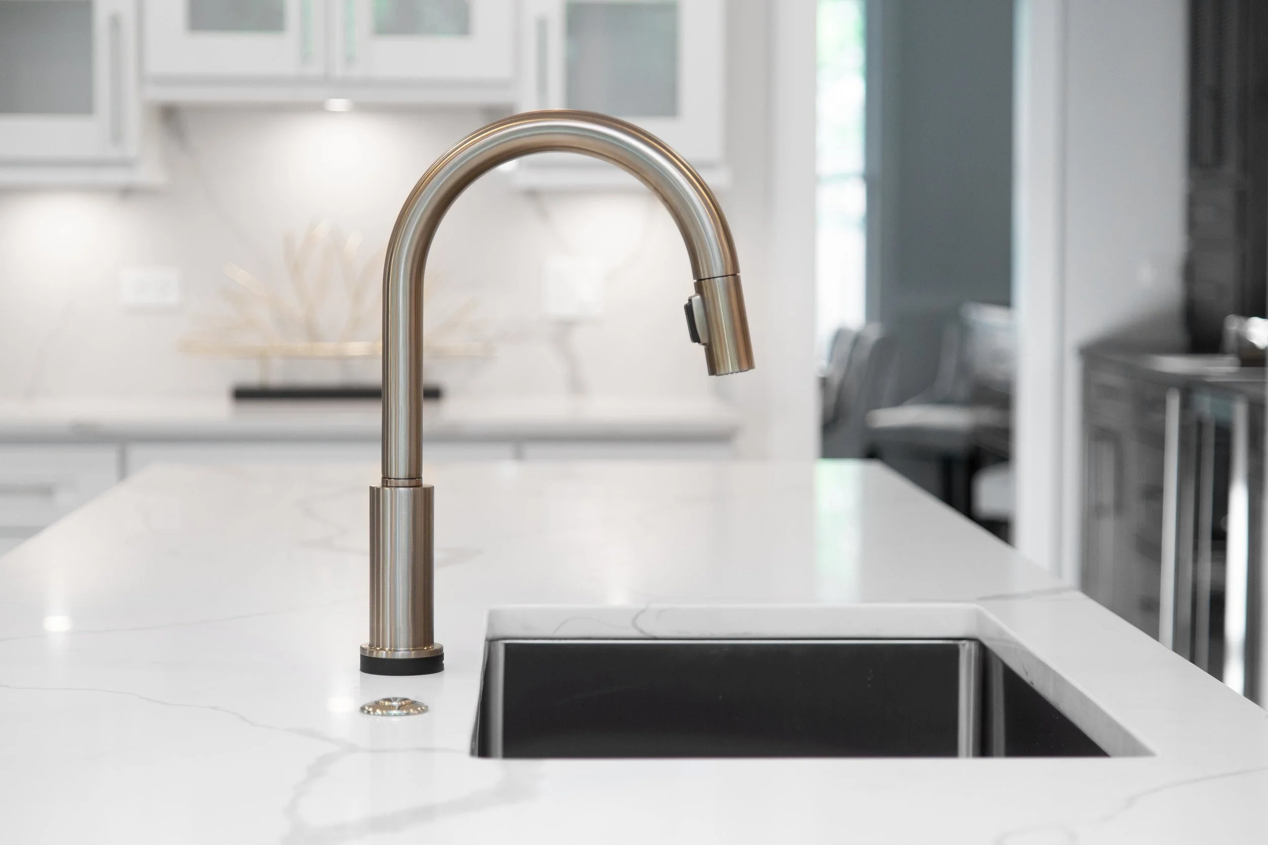 A kitchen sink faucet mounted on a white countertop in a modern kitchen.