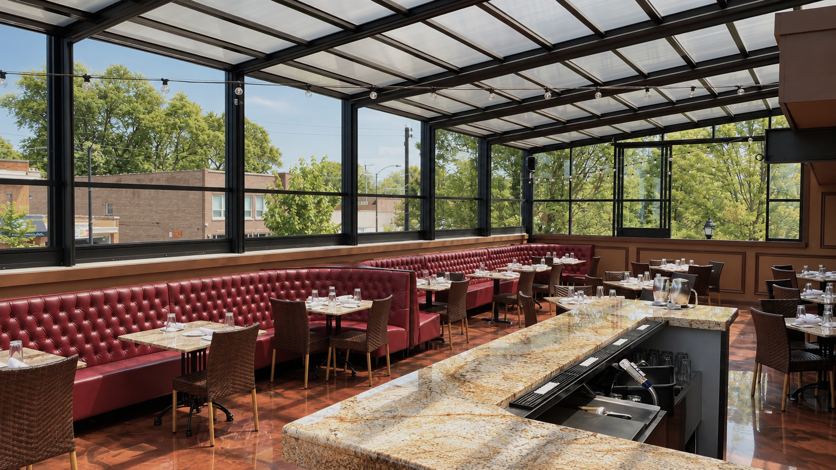 Indoor restaurant with red leather booths, wooden tables, and wicker chairs, large windows with green trees outside, and a granite bar counter in the foreground.