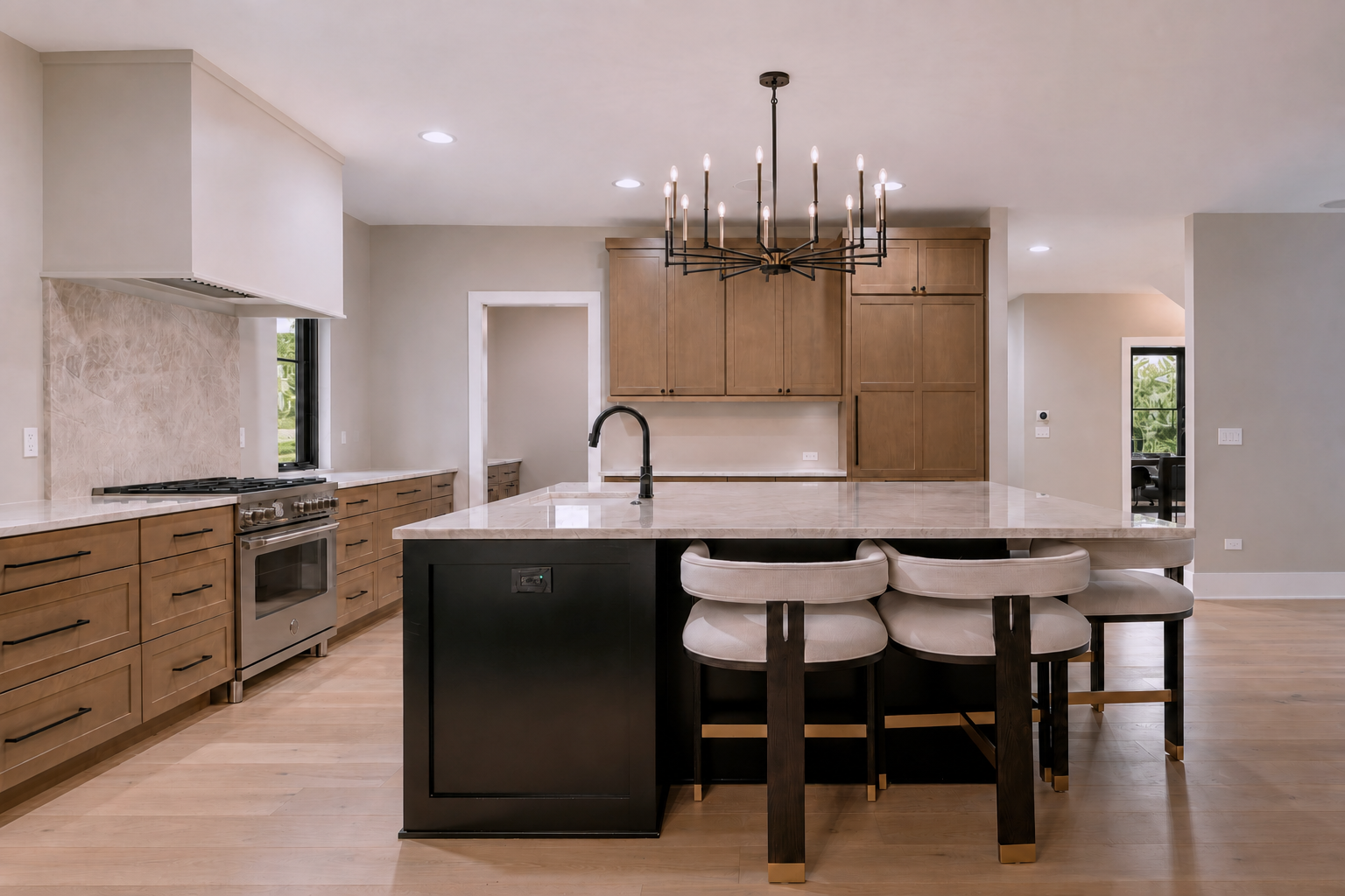 Modern kitchen with wooden cabinets, a large island with a marble countertop, beige bar stools, and a black chandelier overhead.