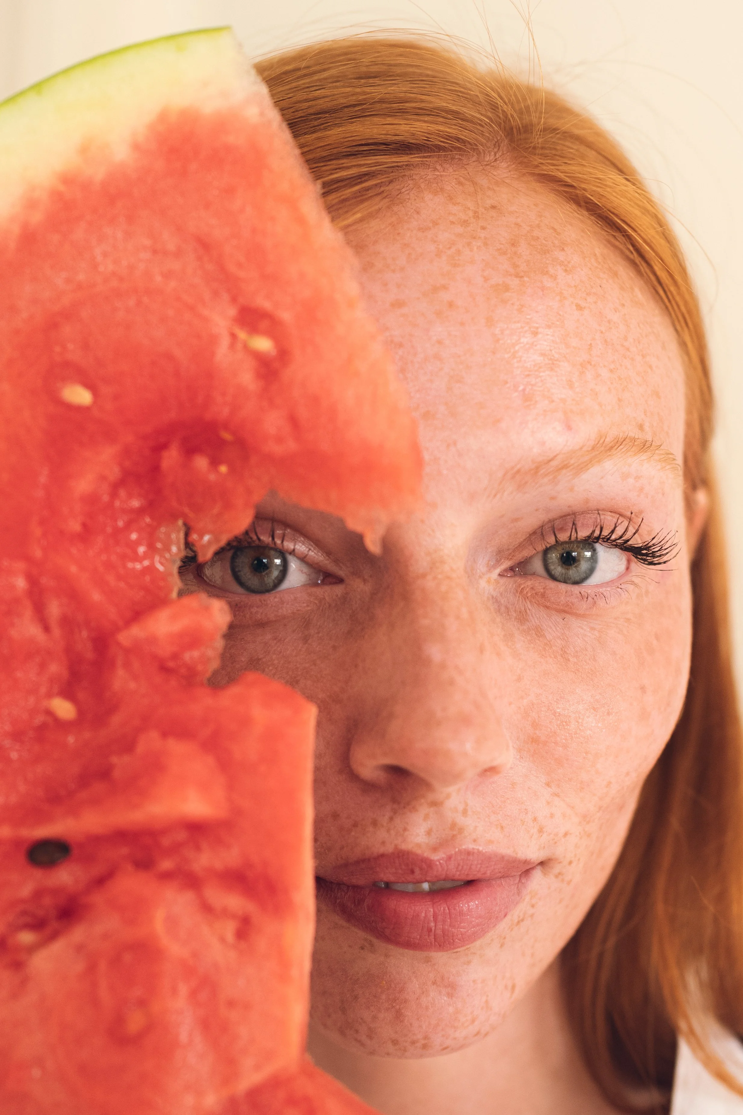 A woman with red hair and freckles holding a slice of watermelon close to her face. Columbus, Ohio, David Kim Photography