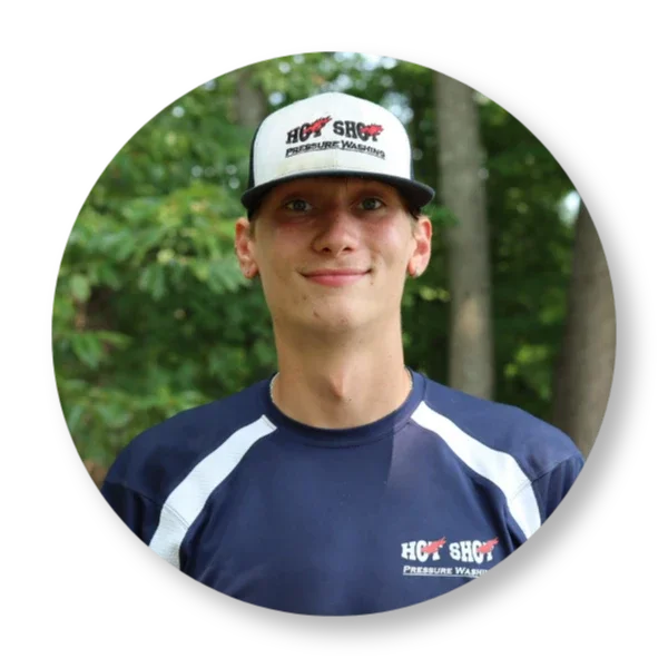 Theo Hot Shot Pressure Washing employee in Salem Virginia smiling in uniform in front of a property.