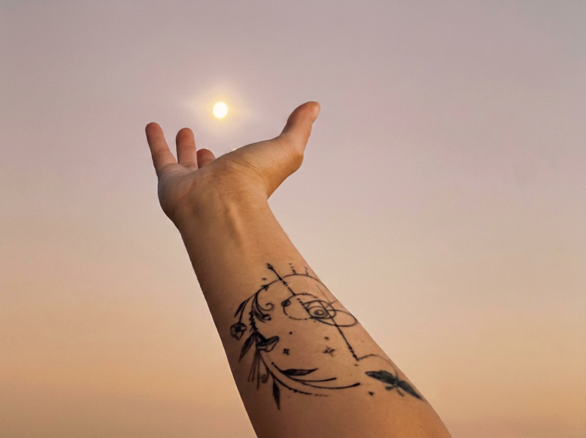 Outstretched arm reaching toward the moon in the night sky.