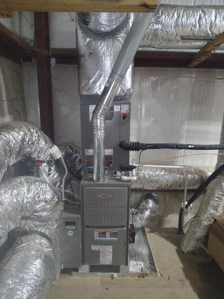 An HVAC furnace and ductwork installation in a basement, with multiple insulated air ducts connected to a Lennox furnace.