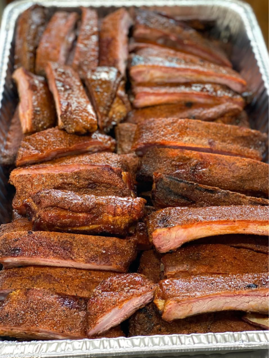 Tray of cooked and seasoned beef ribs cut into individual pieces.