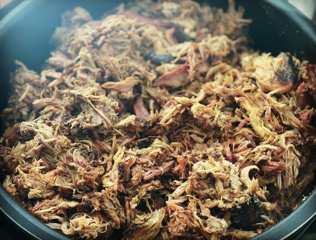 Shredded cooked meat in a large pot or slow cooker.