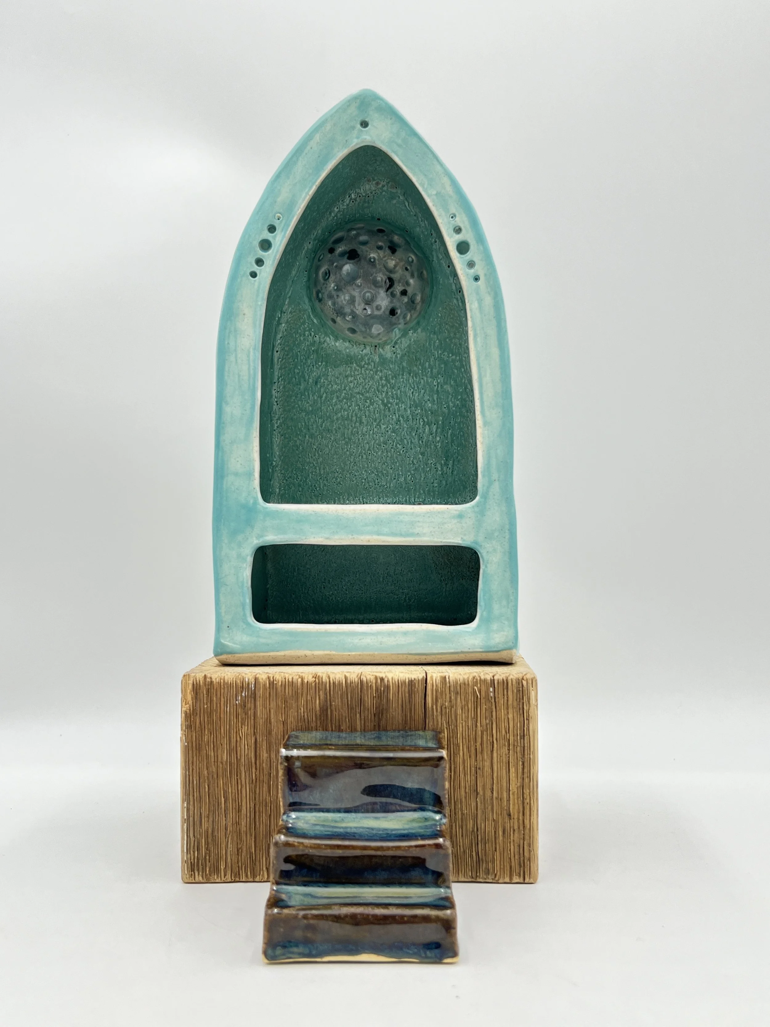  Turquoise shrine on a wooden block with brown stairs leading up to the shrine with a gray moon in the back