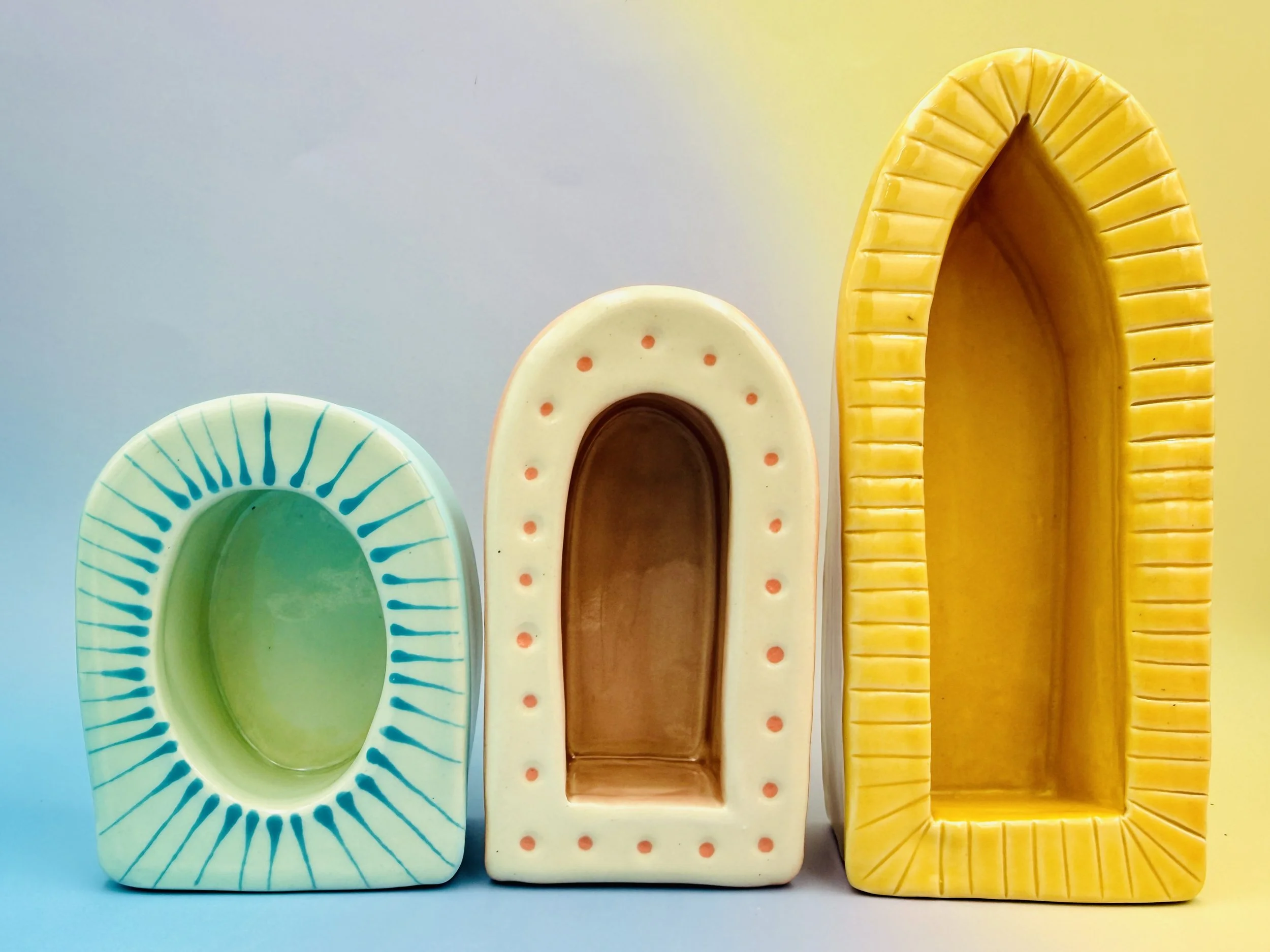 Three colorful ceramic arches on a gradient background. The left one is teal with lines, the middle is cream with dots, and the right is yellow with ridges.