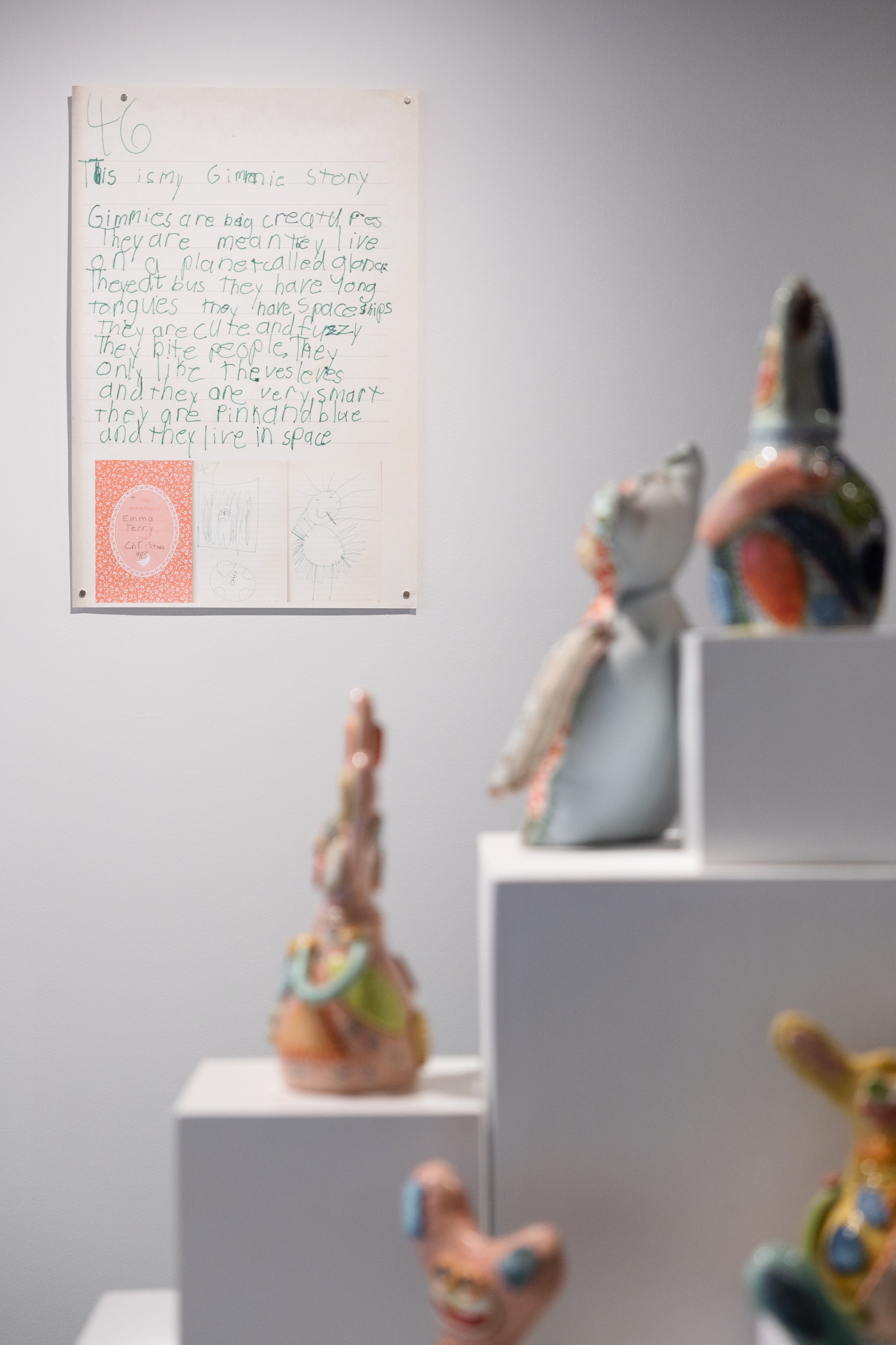 A child’s handwritten story about strange space creatures fills a sheet, with green writing and three small drawings below; imaginative, playful tone.