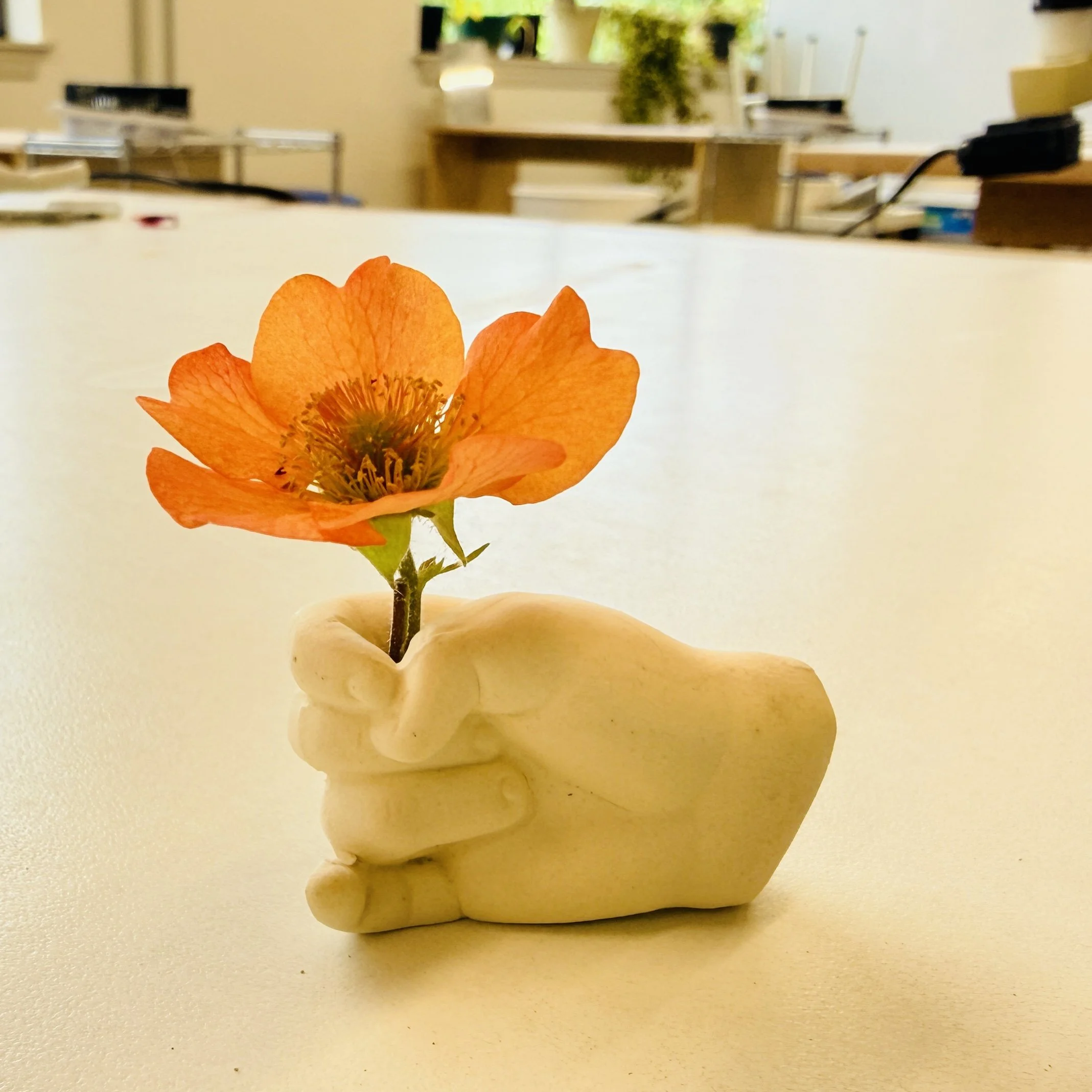 Ceramic vase in the shape of a hand with one flower stem