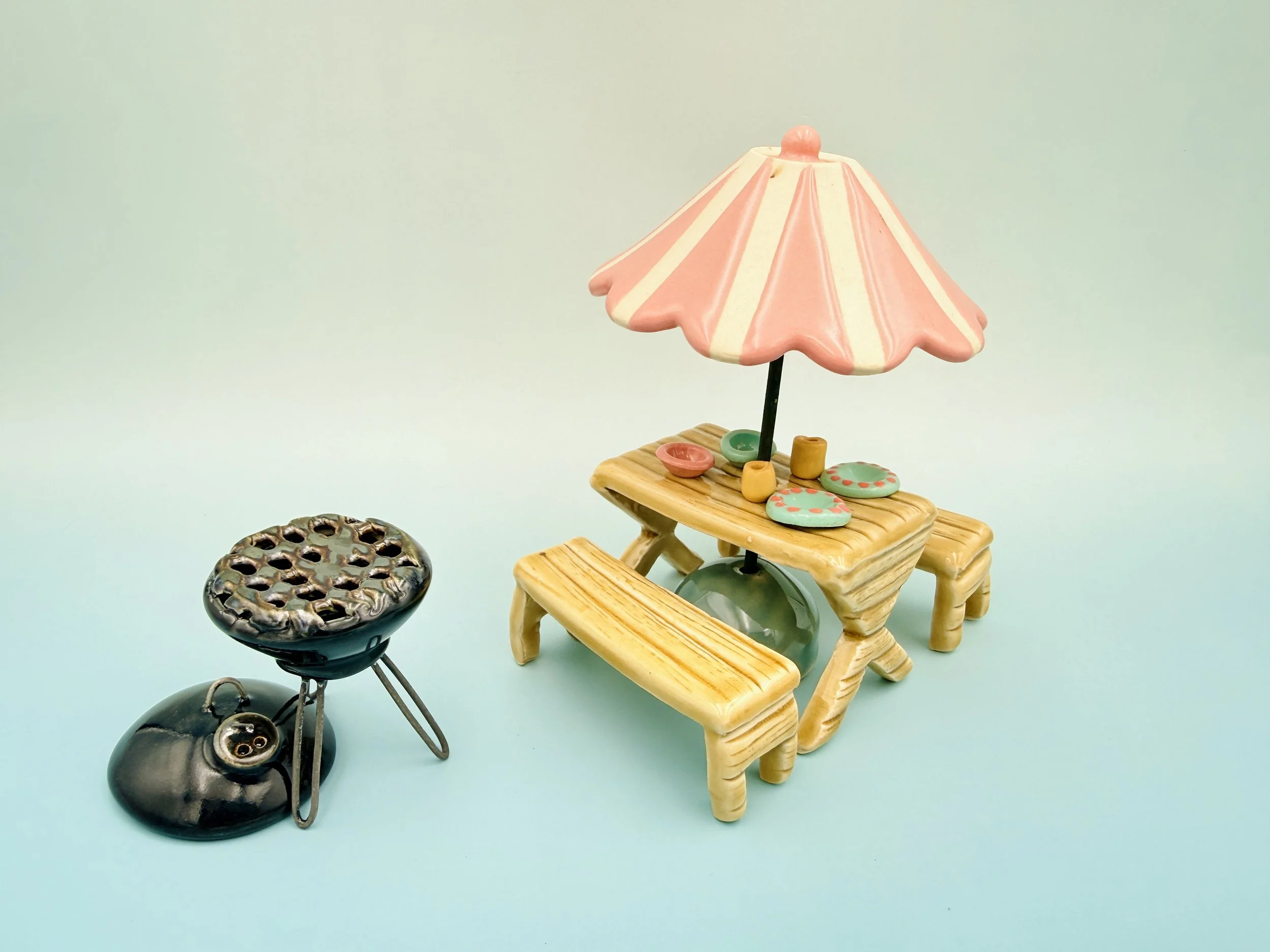 Ceramic picnic table with ceramic grill and pink striped umbrella