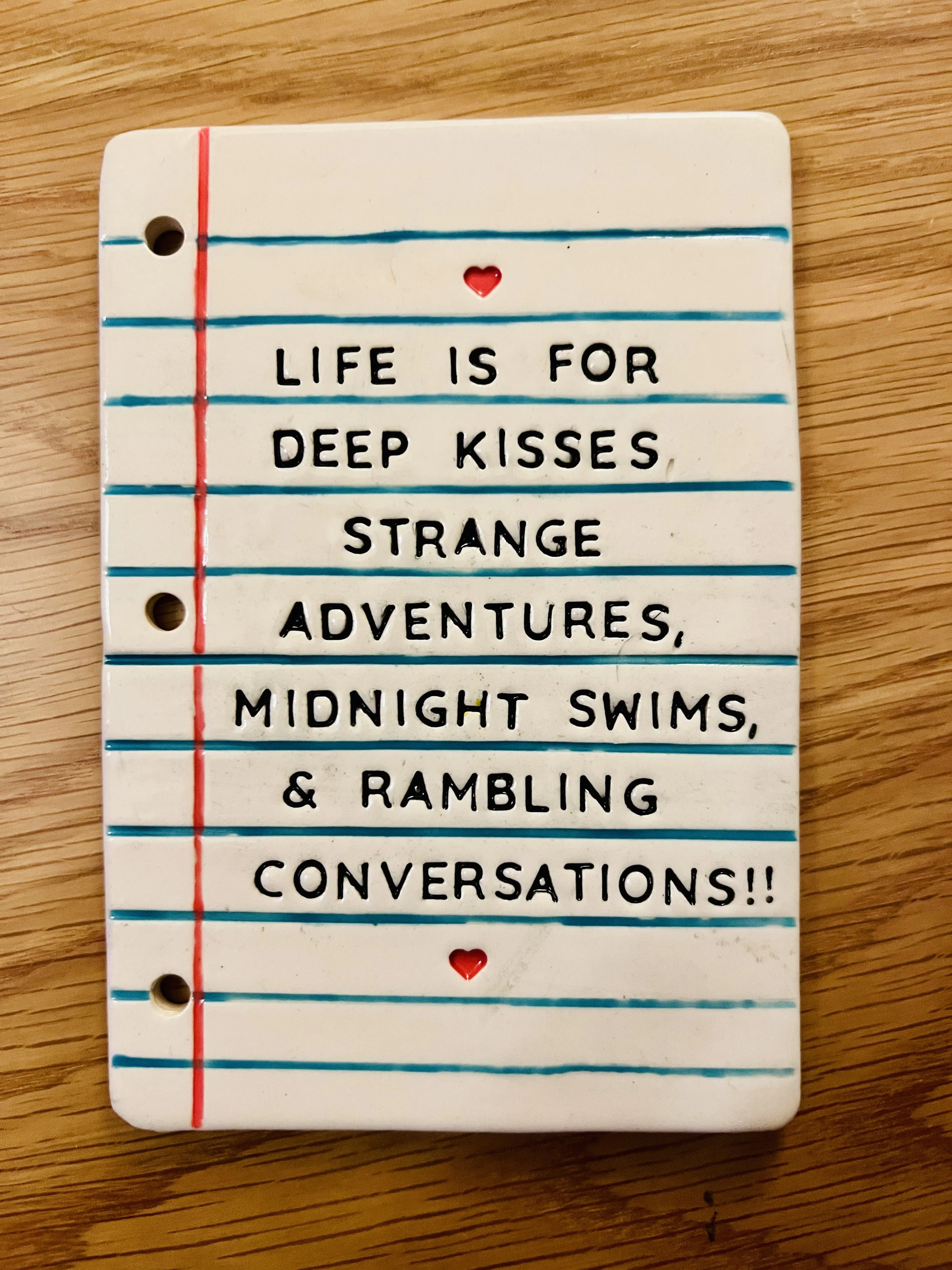  ceramic piece of looseleaf paper with poem that says life is for deep kisses, strange adventures, midnight swims, and rambling conversations