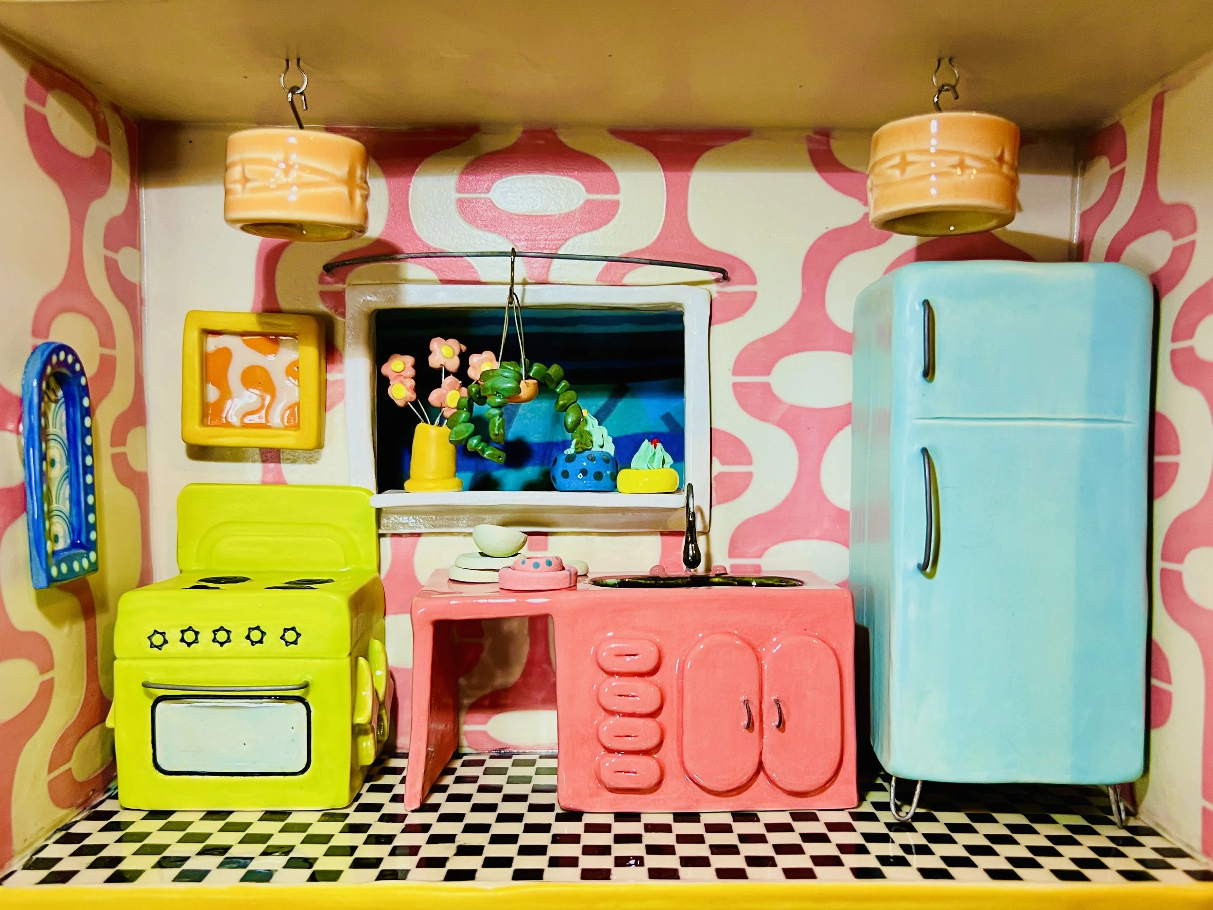  ceramic dollhouse kitchen in a mid-century modern style with a turquoise refrigerator, a pink sink, and a chartreuse oven with two framed pictures, potted plants, and light fixtures on the ceiling