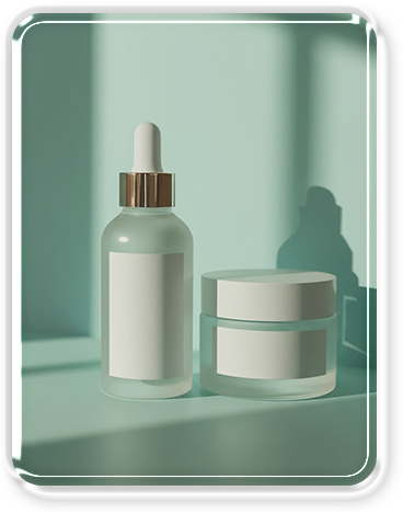 A white dropper bottle and a small white jar with silver accents on a light surface with a greenish background.