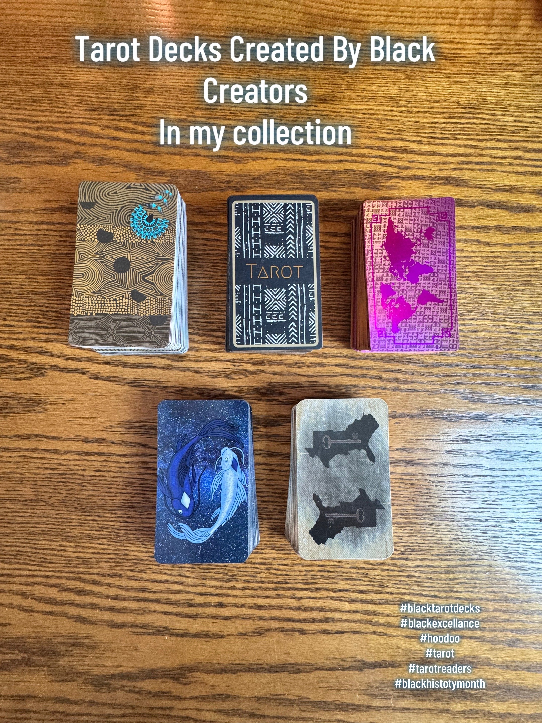 A display of tarot decks on a wooden surface, with a message indicating they are created by Black creators and part of a collection. The image includes a card with a fish illustration and hashtags related to tarot and Black history month.